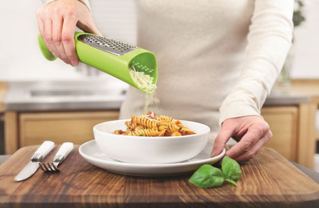 Zeal Tower Grater in vibrant red or green, designed for mess-free cheese grating and easy pouring directly onto dishes.