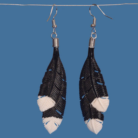 Elegant black huia feather earrings, handcrafted from beef bone, showcasing unique carvings and cultural Mâori significance.