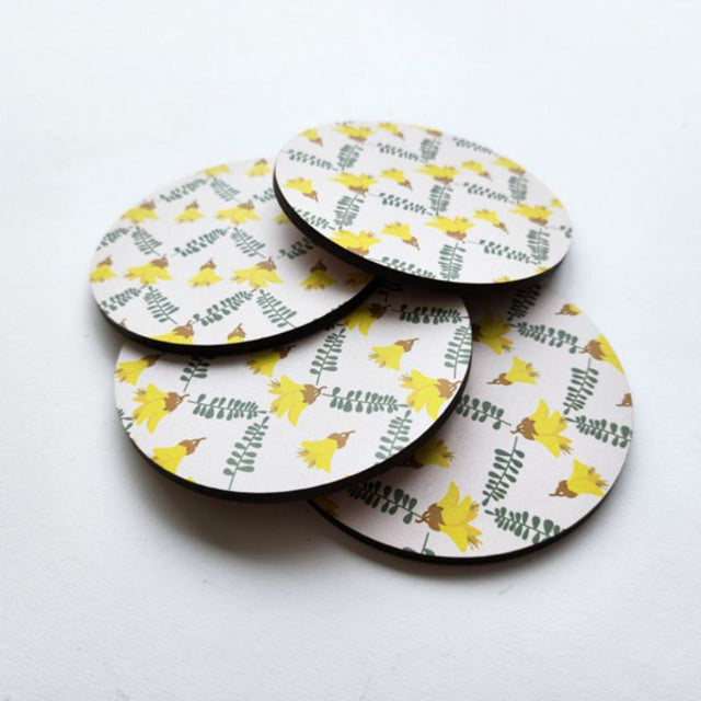 10cm Kowhai coaster with vibrant yellow flower design, made from durable MDF and featuring a cork base for stability.