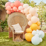 Muted pastel balloon arch kit featuring 75 latex balloons in coral, pink, peach, yellow, and mint green for celebrations.