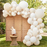 Nude and white balloon arch kit with 80 balloons and 5 cream paper fans for elegant event decor.