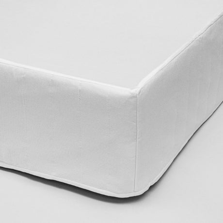 Elegant white quilted bed skirt enhancing older bed base, made of durable soft brushed polyester for lasting style.