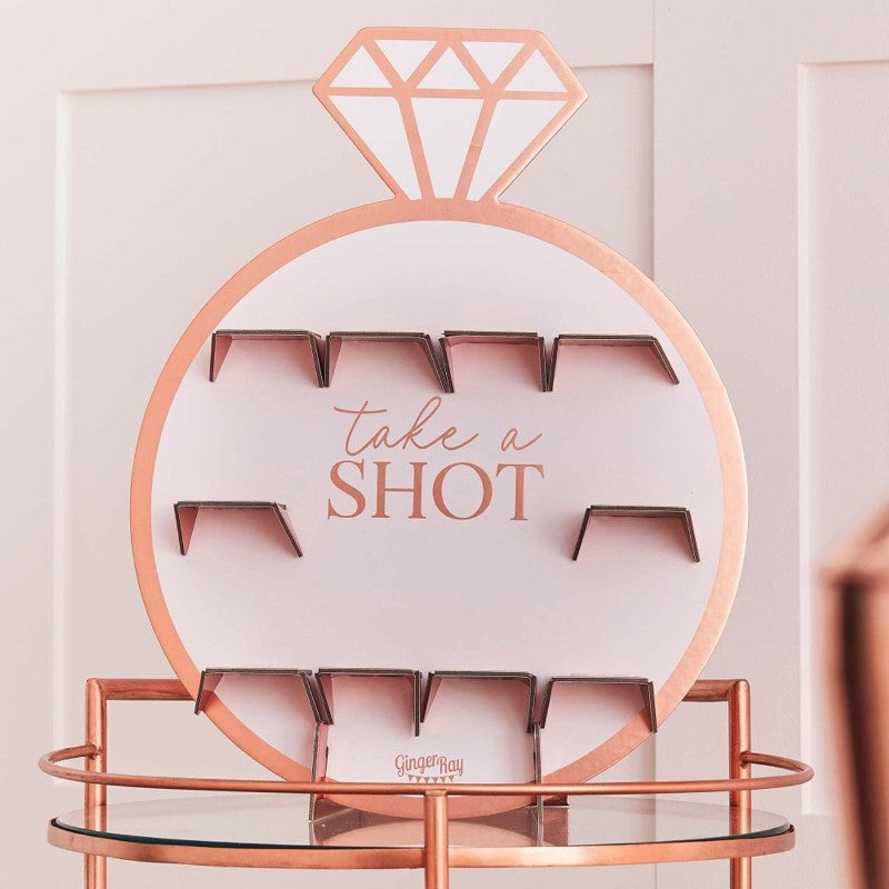 Rose gold drinks shot wall decorated for a hen party, featuring holders for shots and a stylish design.