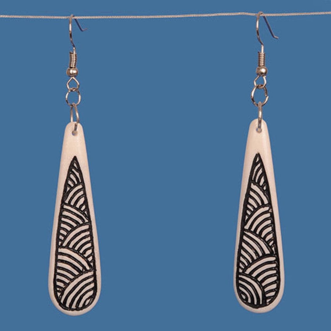 Handcrafted bone drop earrings with black patterned stain, inspired by M?ori tattoo art, measuring 55 mm x 15 mm.