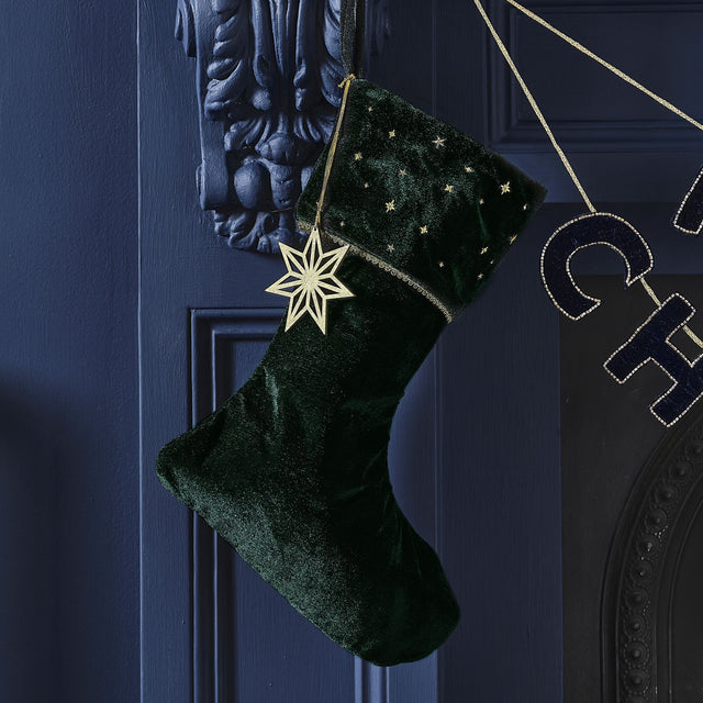 Luxurious green velvet Christmas stocking embroidered with a gold star charm, perfect for festive decor and sustainable traditions.