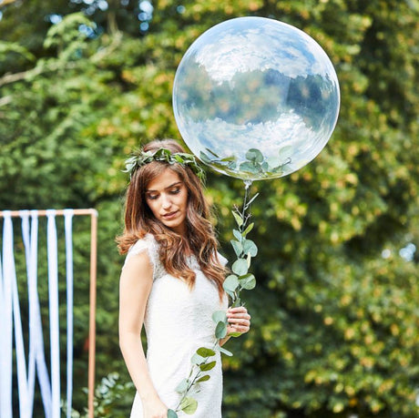 Clear orb balloon adorned with lush green vines, perfect for enhancing a natural wedding theme.